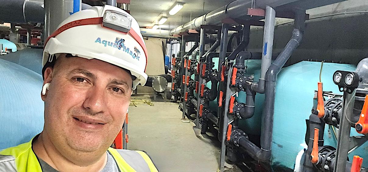 An Aqua Magic engineer in a branded hard hat inside a filtration plant room
