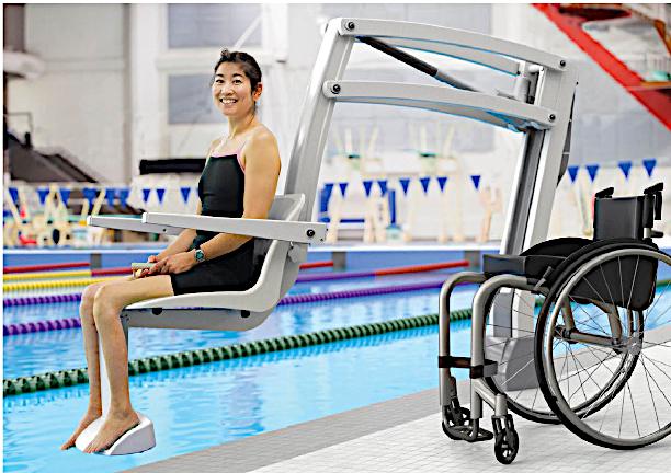 Swimmer using a pool lift seat next to her wheelchair