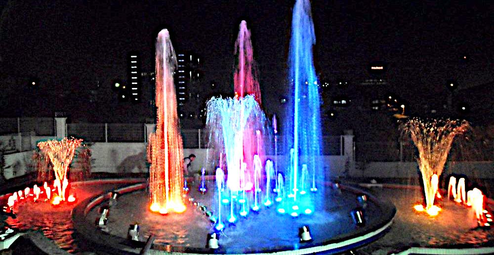 Illuminated fountain show at night in red, pink and blue