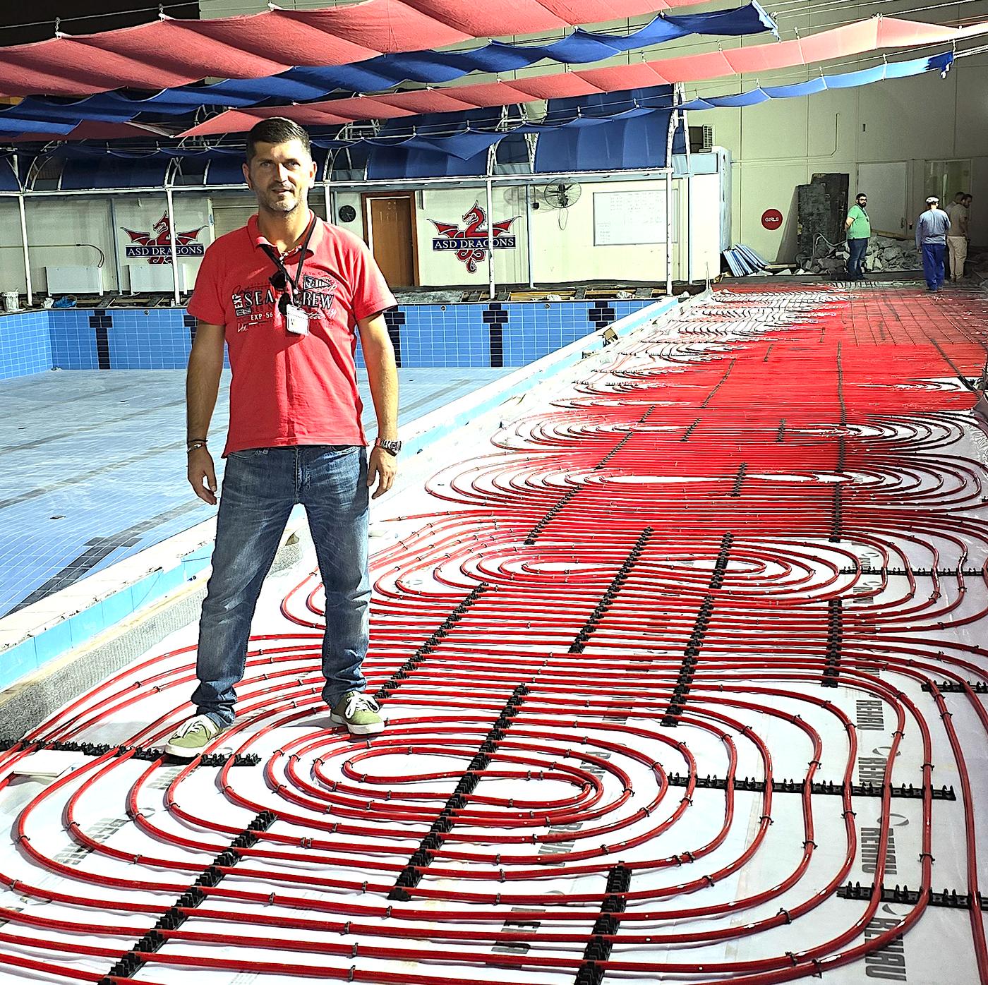 Engineer standing beside red underfloor piping loops
