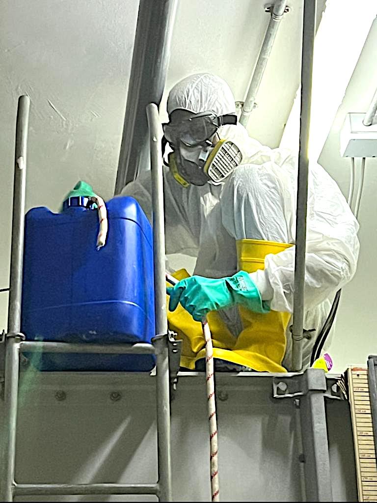 Technician in a respirator handling disinfection chemicals