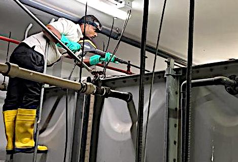 Technician in boots inspecting a tank from a ladder
