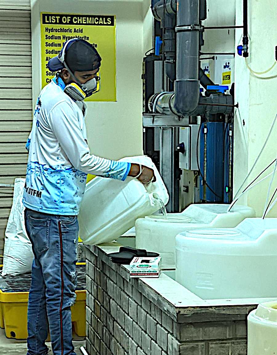 Technician in a respirator refilling chemical containers